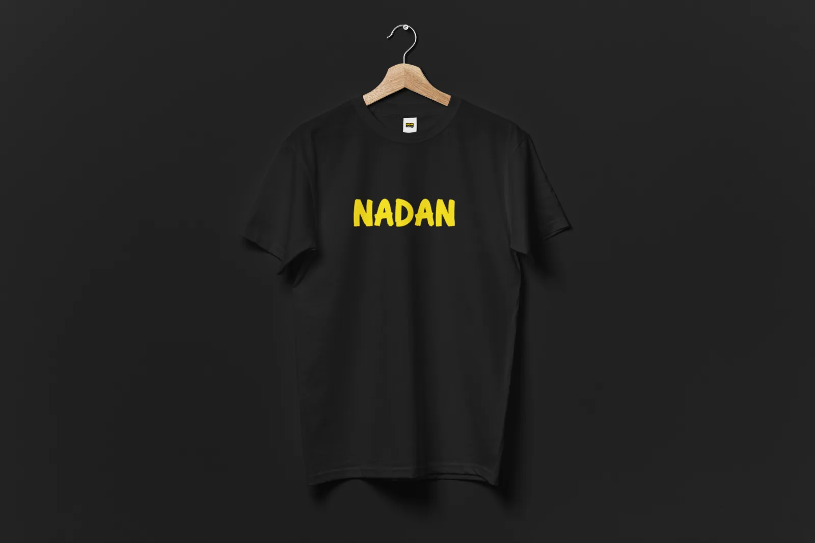 A black Nadan Drip t-shirt on a hanger with the yellow wordmark print