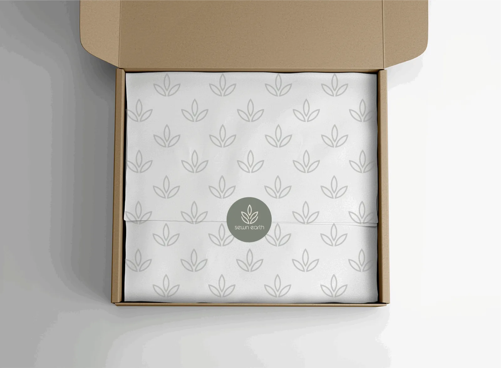 Folded Sewn Earth branded fabric with a leaf pattern inside a kraft mailer box