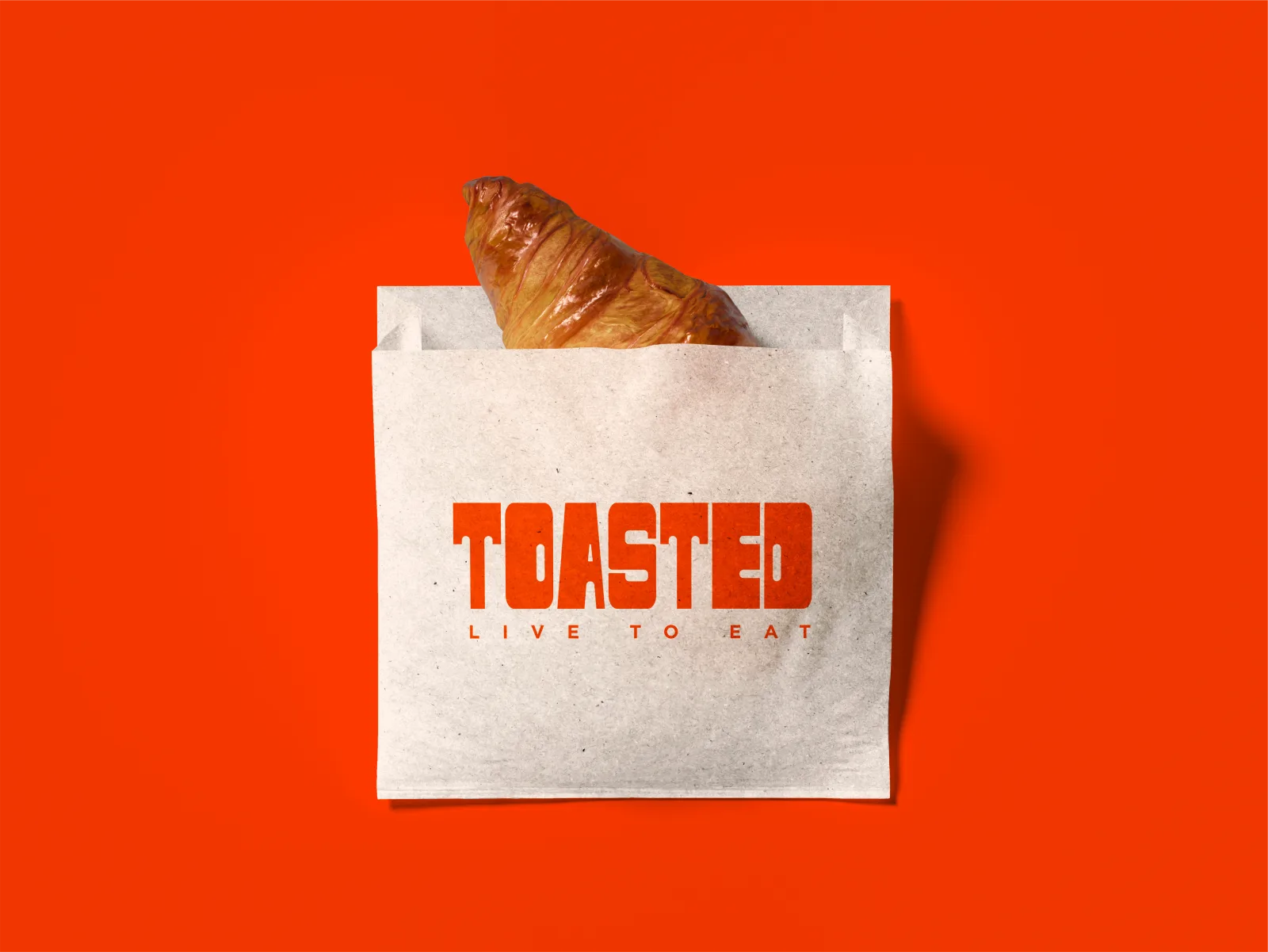 A croissant sandwich in a Toasted branded paper bag